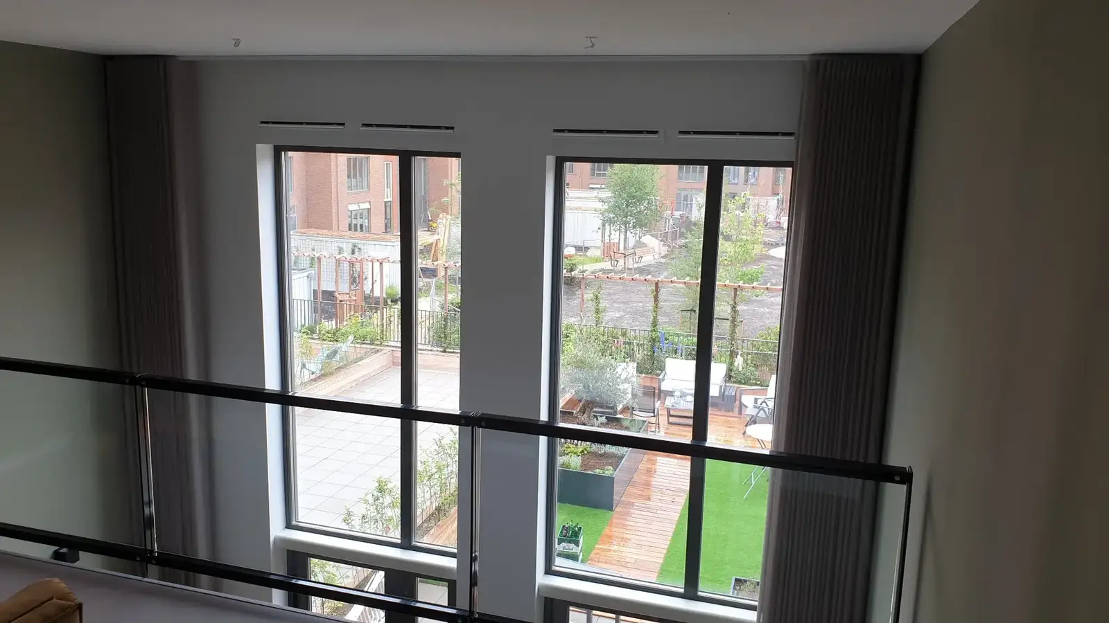 Gordijnen bij een hoge pui in een woning met vide