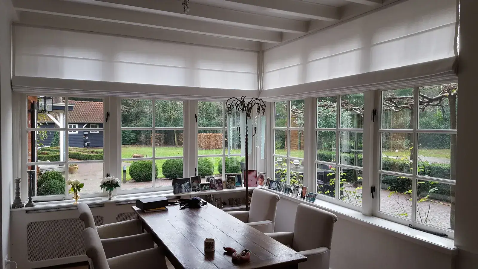 Brede witte vouwgordijnen bij hoekramen
