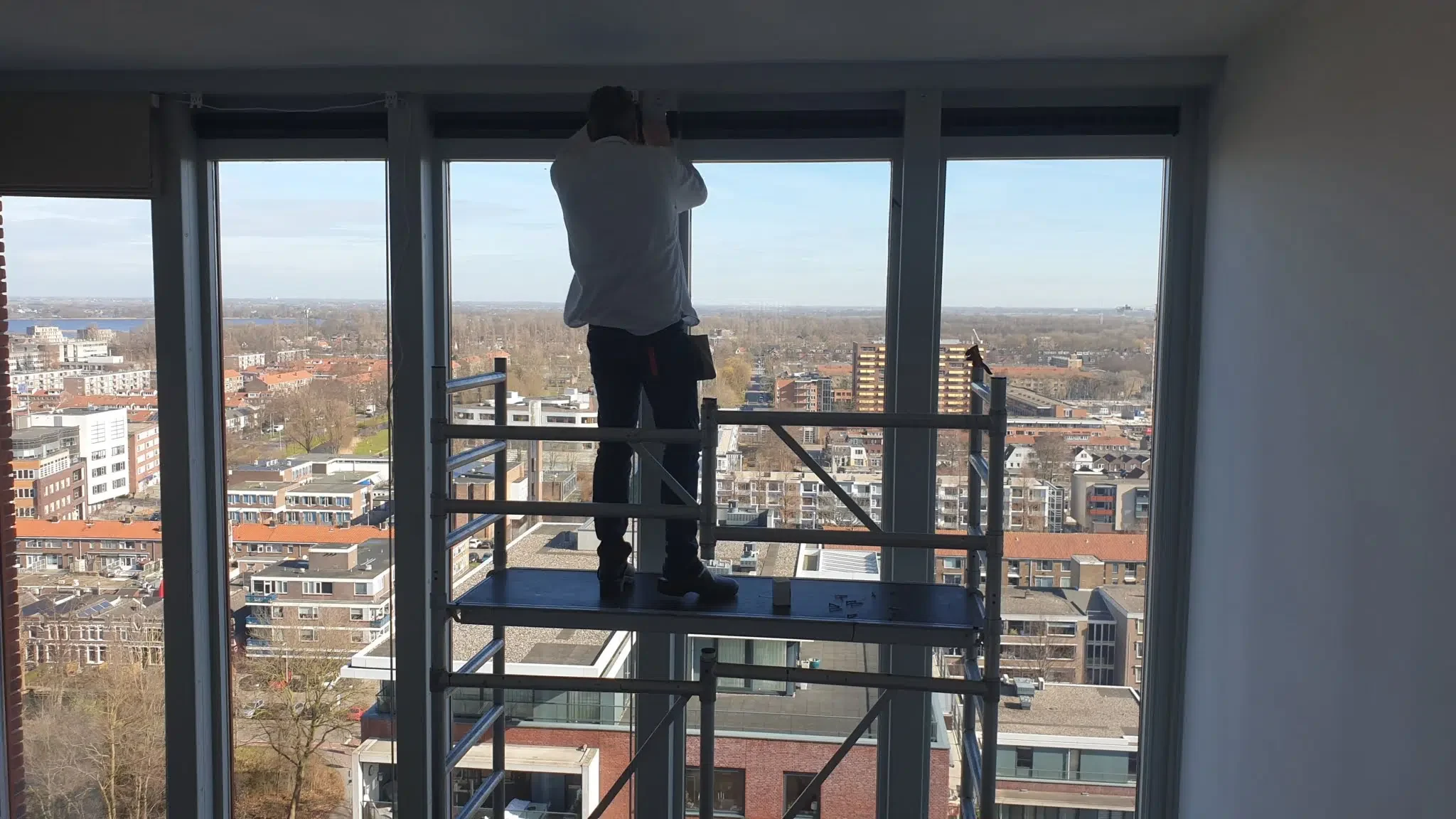 Montage van hoog elektrisch vouwgordijn vanaf een steiger bij hoge ramen