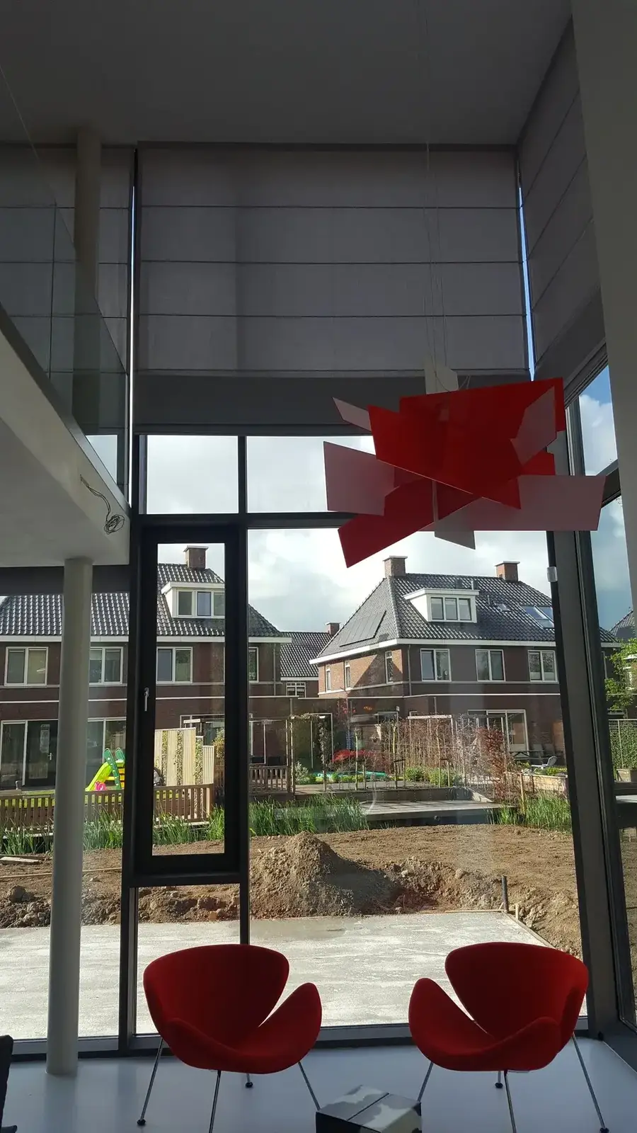 Elektrische hoge vouwgordijnen van circa zes meter bij een hoge glasgevel