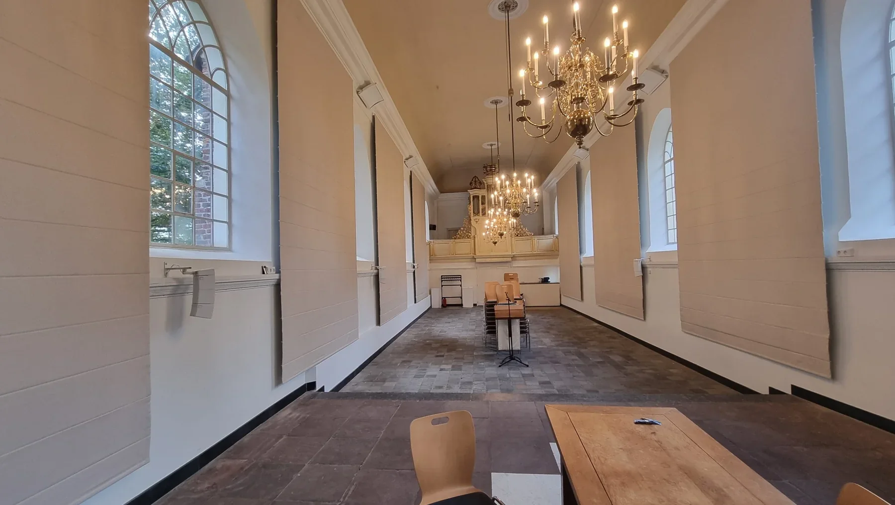 Afgewerkt kerkinterieur met meerdere hoge lichte vouwgordijnen