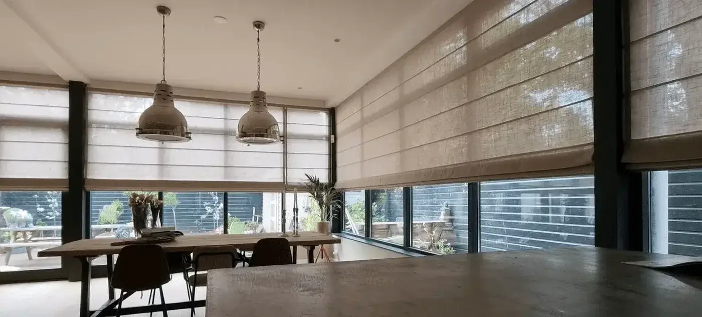 Lichte vouwgordijnen rondom een eethoek met grote ramen