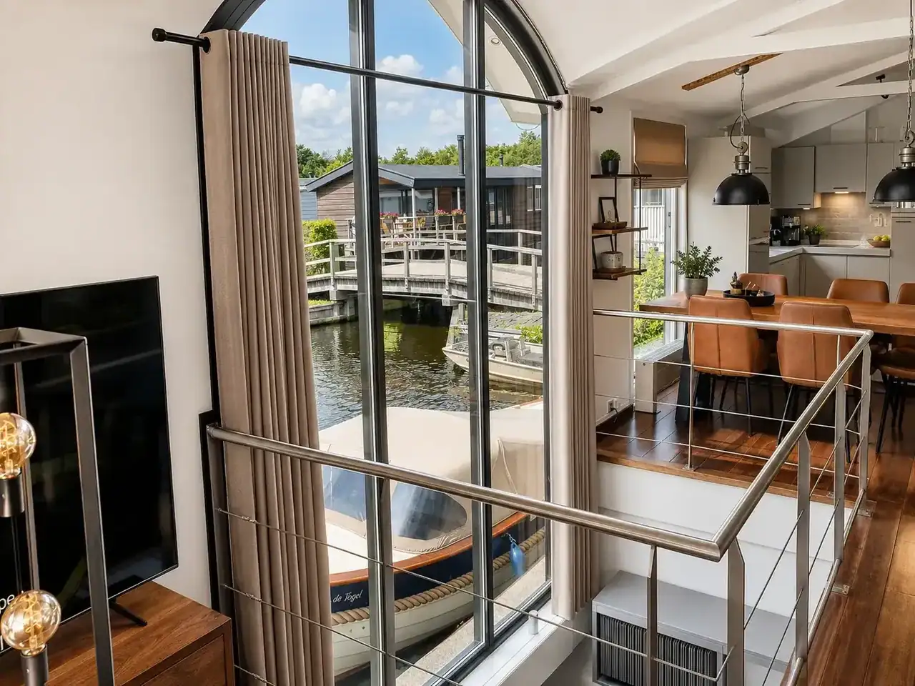 Lange gordijnen bij hoge ronde glasdeur in lichte woonkeuken