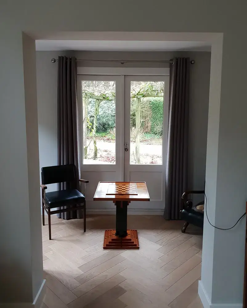 Taupe gordijnen met ingeslagen ringen aan een metalen gordijnroede