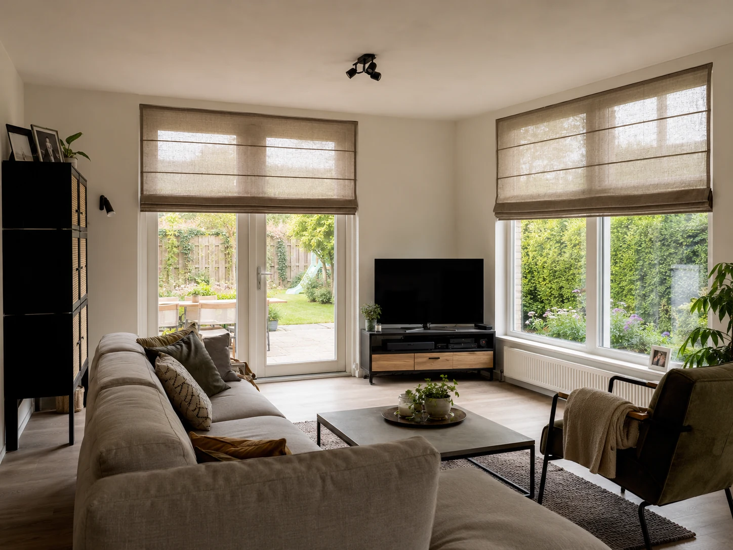 Taupe lichtdoorlatende vouwgordijnen in een woonkamer met tuinzicht